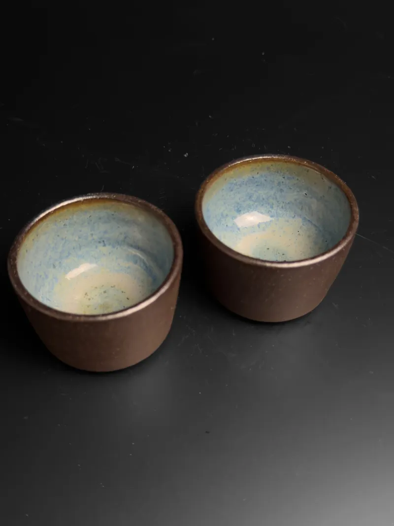 Pair of brown cups with pale blue interiors
