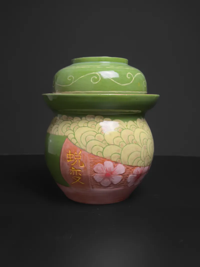 Green and pink lidded jar with a carved wave pattern