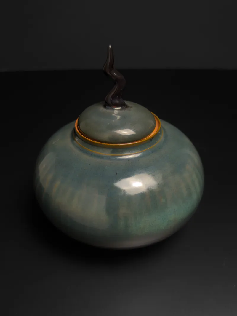 Round green lidded jar with a twisted dark knob