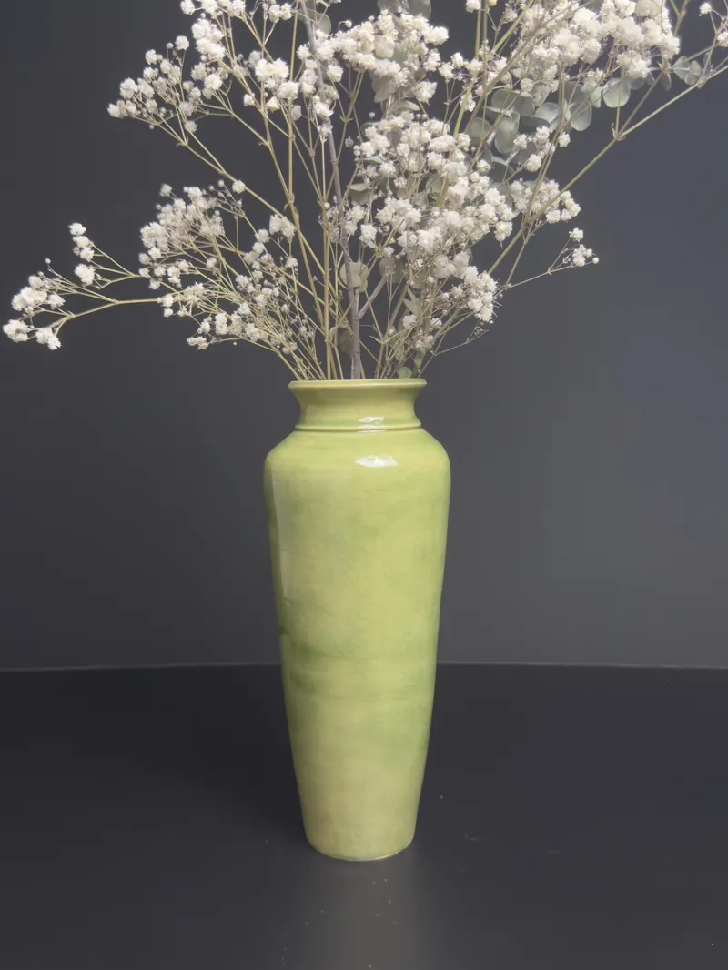 Tall green vase holding dried flowers