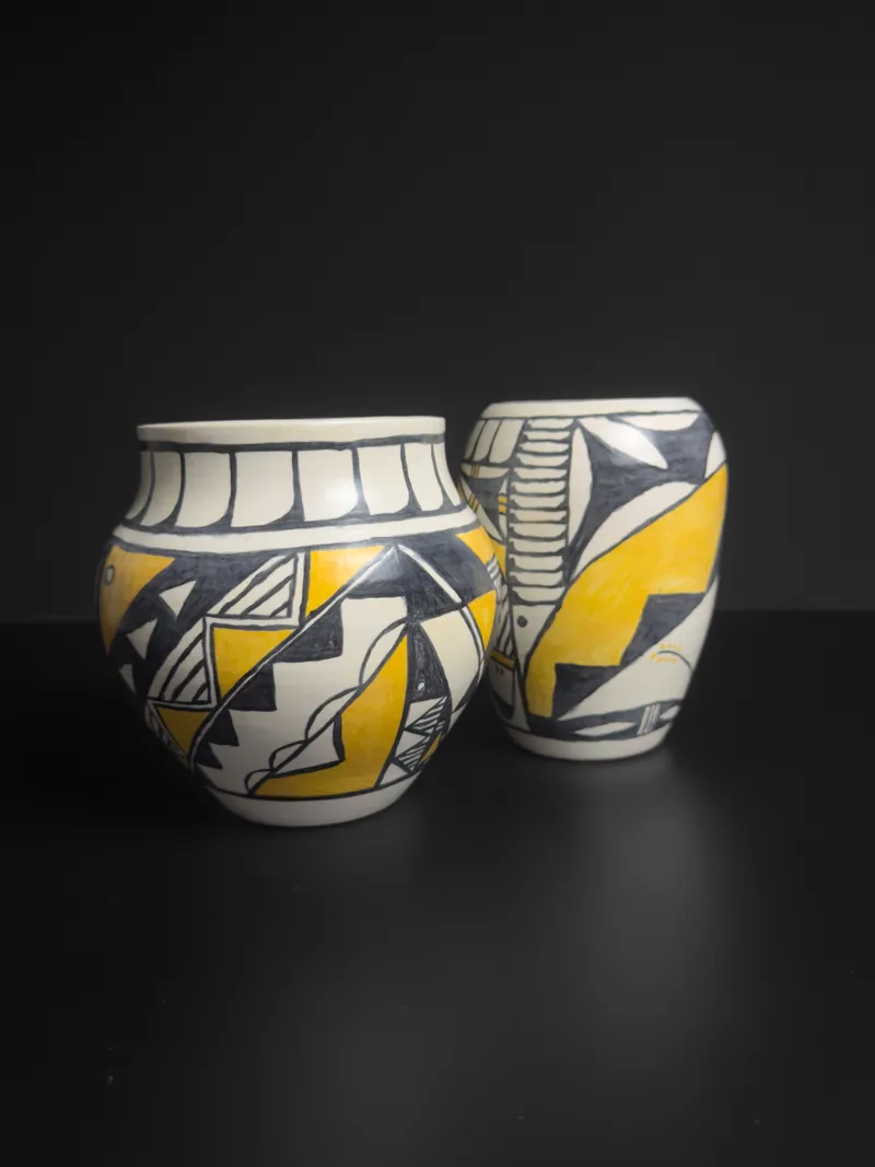 Two jars painted in black and yellow geometric patterns