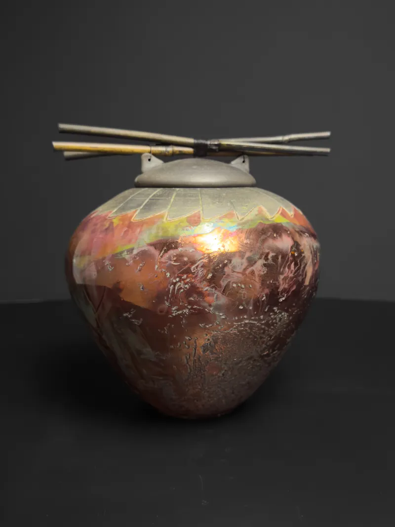 Raku-fired lidded jar with metallic luster and a twig handle