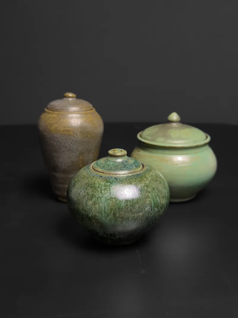 Three lidded jars in green and brown glazes